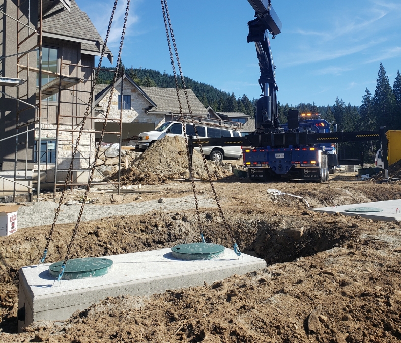 Workers installing a precast concrete septic tank on a construction site